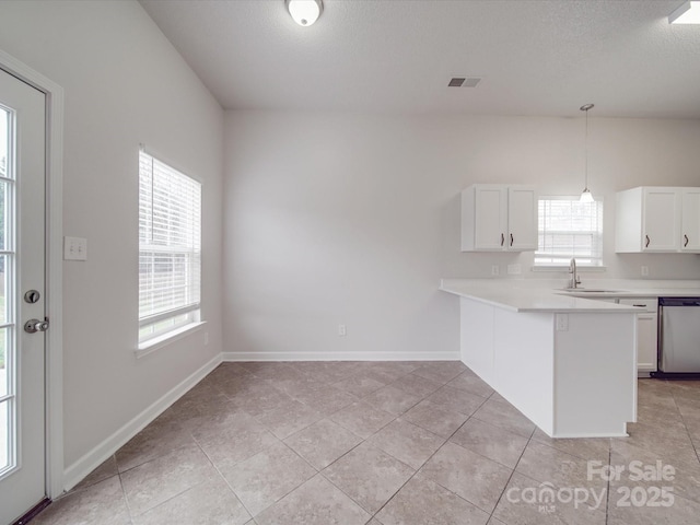 kitchen with visible vents, white cabinetry, light countertops, stainless steel dishwasher, and hanging light fixtures