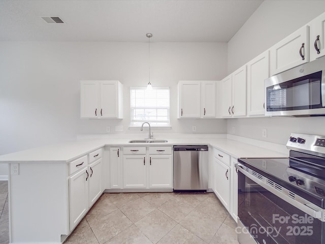 kitchen featuring a peninsula, white cabinetry, stainless steel appliances, and a sink