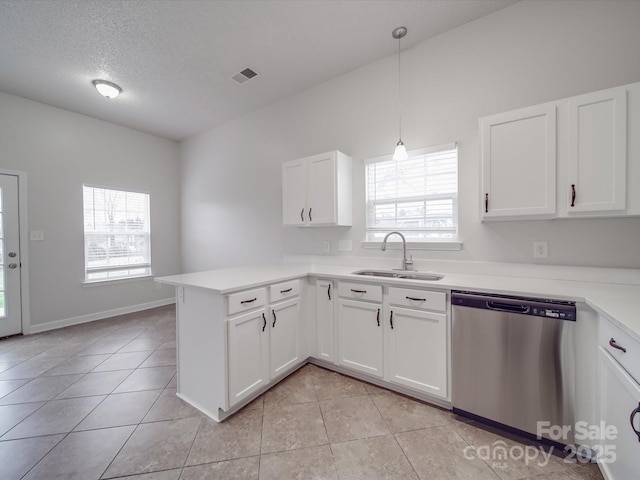 kitchen featuring light tile patterned floors, a peninsula, a sink, white cabinetry, and dishwasher