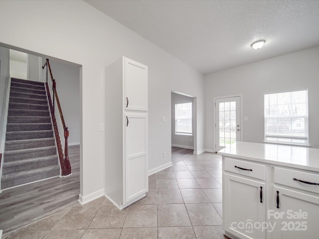 interior space featuring stairs, a textured ceiling, baseboards, and light tile patterned floors