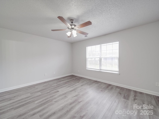 empty room featuring ceiling fan, baseboards, and wood finished floors