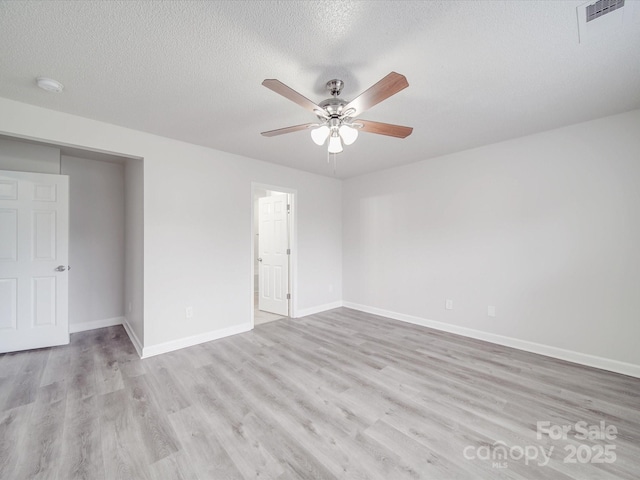 unfurnished room with a ceiling fan, visible vents, light wood-style flooring, and baseboards