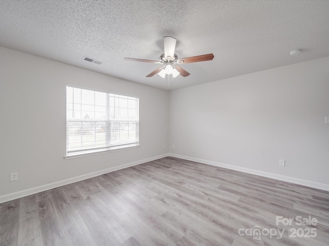 empty room featuring light wood-style flooring, visible vents, and baseboards