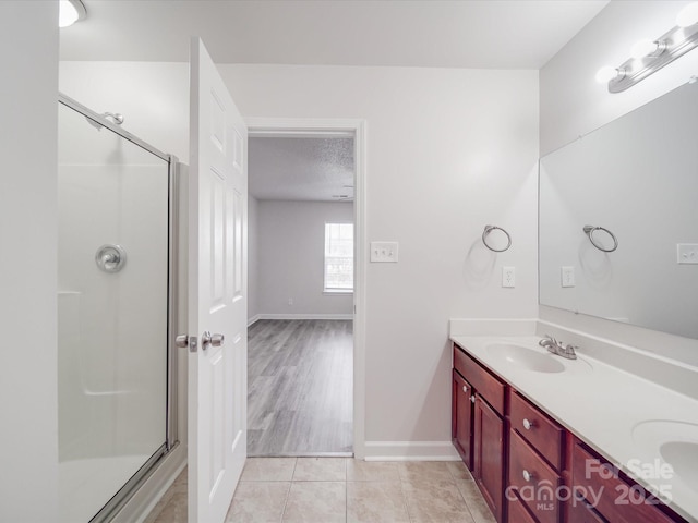 bathroom with double vanity, tile patterned flooring, a sink, and a shower stall