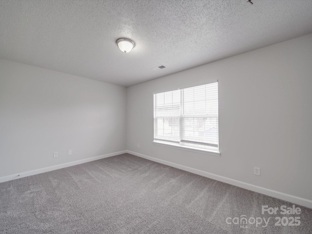 carpeted empty room with visible vents, baseboards, and a textured ceiling