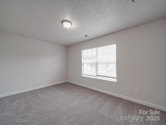 carpeted empty room with visible vents, baseboards, and a textured ceiling