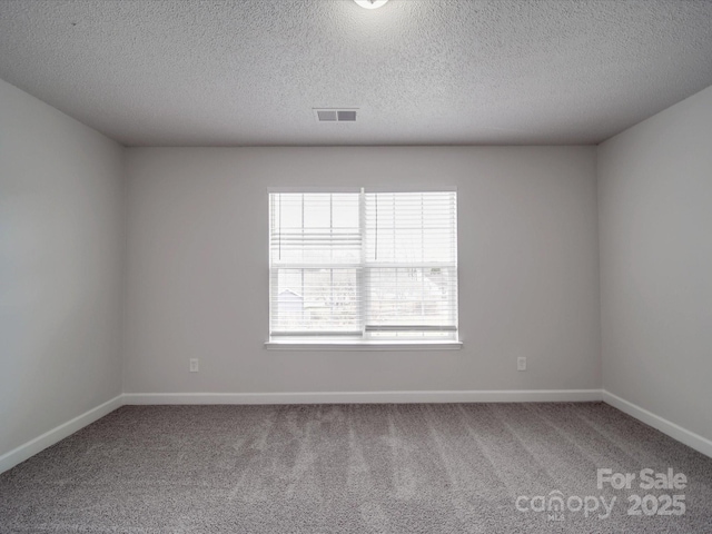 unfurnished room with carpet, a textured ceiling, visible vents, and baseboards