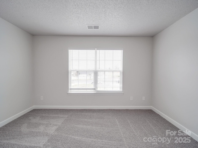 unfurnished room featuring carpet floors, baseboards, visible vents, and a textured ceiling