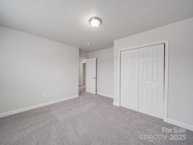 unfurnished bedroom featuring a textured ceiling, a closet, carpet flooring, and baseboards