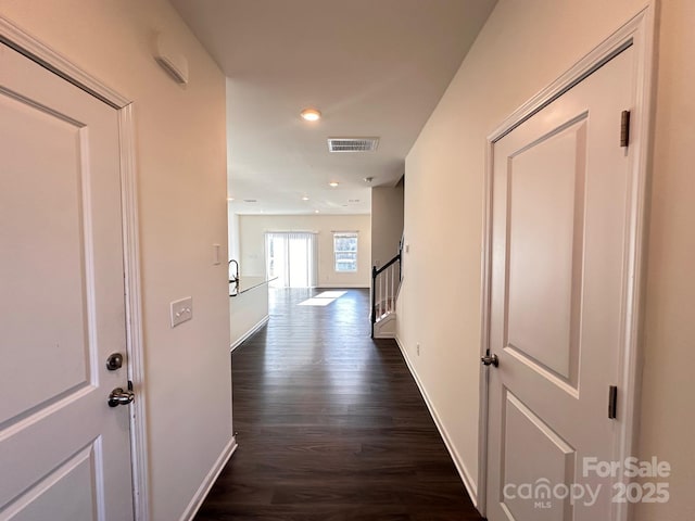 hall featuring dark wood-style floors, recessed lighting, visible vents, baseboards, and stairs