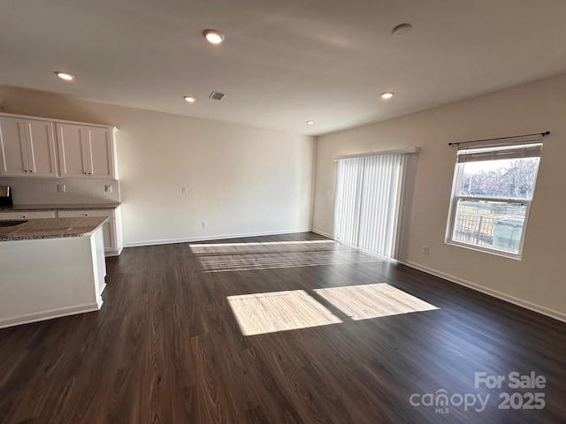 unfurnished living room featuring dark wood-style floors, baseboards, visible vents, and recessed lighting