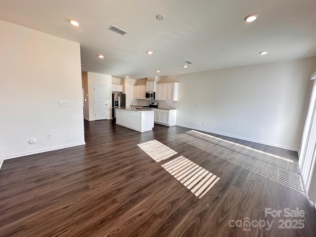 unfurnished living room featuring recessed lighting, dark wood-style flooring, a sink, visible vents, and baseboards