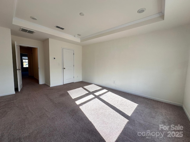 unfurnished bedroom with dark colored carpet, a tray ceiling, visible vents, and baseboards