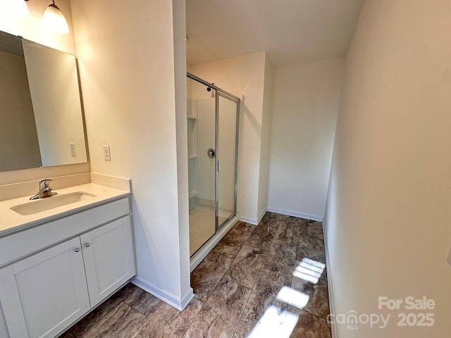 bathroom with a stall shower, marble finish floor, vanity, and baseboards