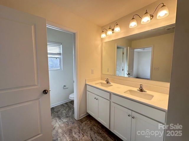 bathroom with visible vents, a sink, toilet, and double vanity