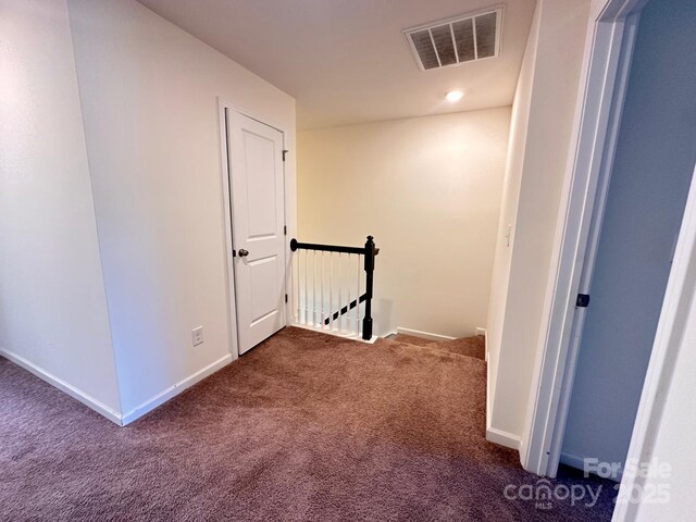 corridor featuring baseboards, visible vents, dark carpet, and an upstairs landing