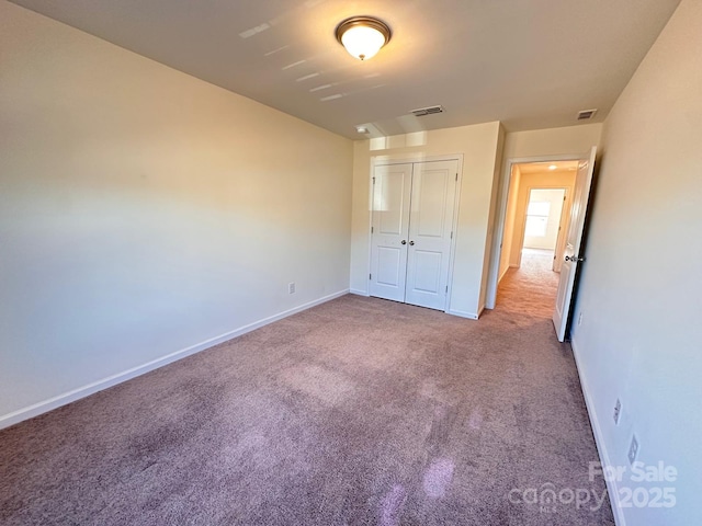 unfurnished bedroom featuring carpet floors, baseboards, visible vents, and a closet