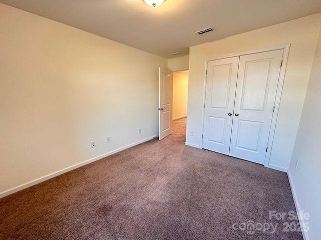 unfurnished bedroom with a closet, carpet flooring, visible vents, and baseboards