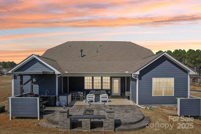 back of property at dusk with outdoor lounge area, a patio, and roof with shingles