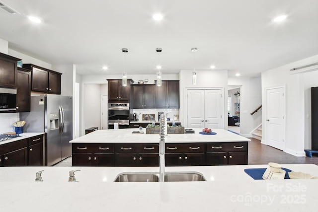 kitchen with visible vents, a kitchen island, light countertops, appliances with stainless steel finishes, and tasteful backsplash