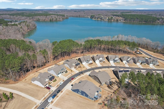 drone / aerial view with a residential view, a wooded view, and a water view