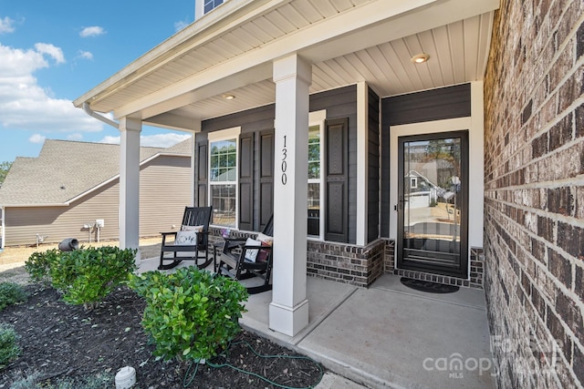 entrance to property featuring brick siding and covered porch