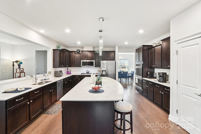 kitchen with appliances with stainless steel finishes, a center island, light countertops, and a sink