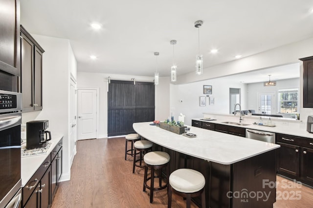 kitchen with a sink, a center island, a barn door, appliances with stainless steel finishes, and light countertops