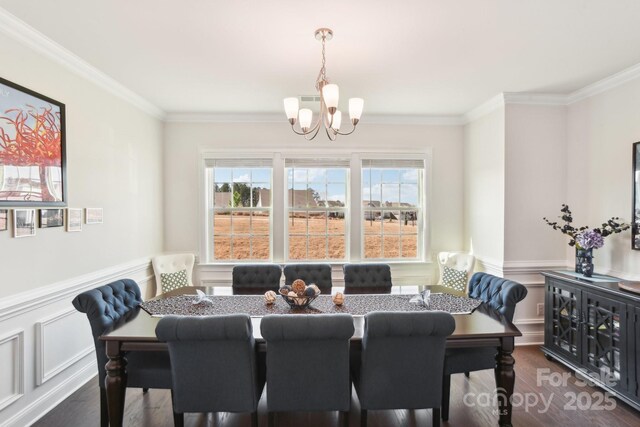 dining space with a wainscoted wall, crown molding, dark wood-style flooring, and a chandelier