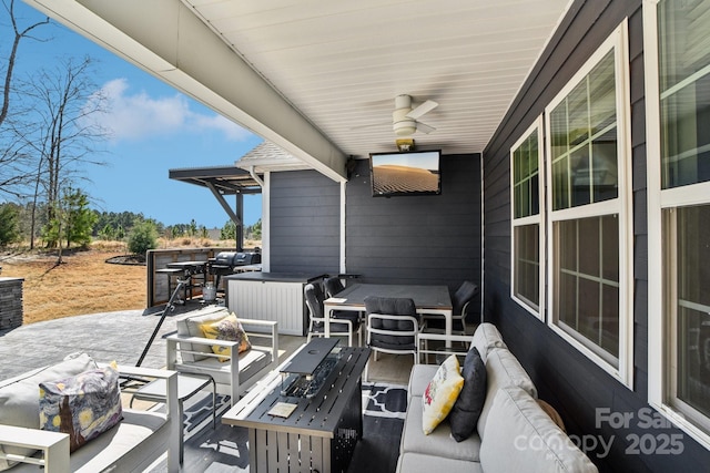 view of patio with a hot tub, an outdoor living space with a fire pit, and a ceiling fan