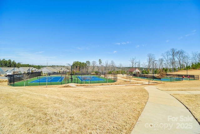 view of community featuring a tennis court and fence