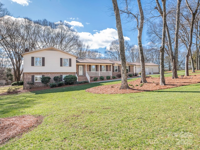 split level home with brick siding, a front lawn, a porch, a chimney, and a garage