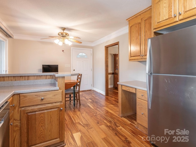 kitchen with stainless steel appliances, light wood-style floors, crown molding, and light countertops