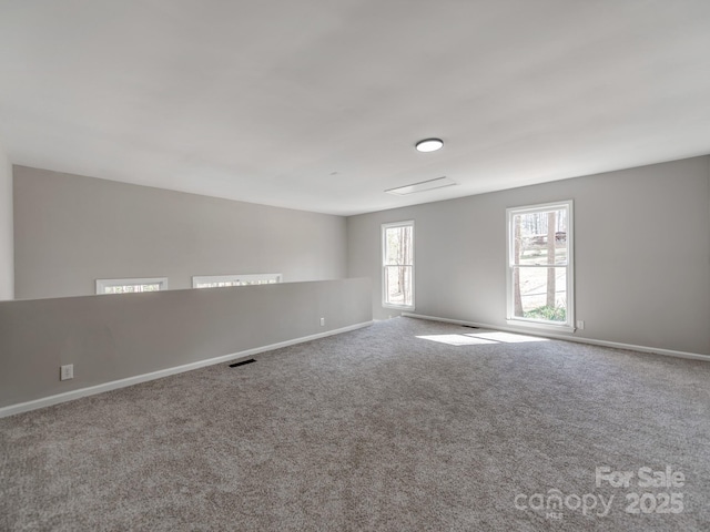 spare room featuring carpet, visible vents, and baseboards