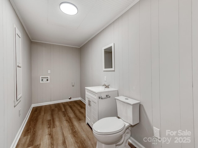 bathroom featuring toilet, ornamental molding, vanity, wood finished floors, and baseboards