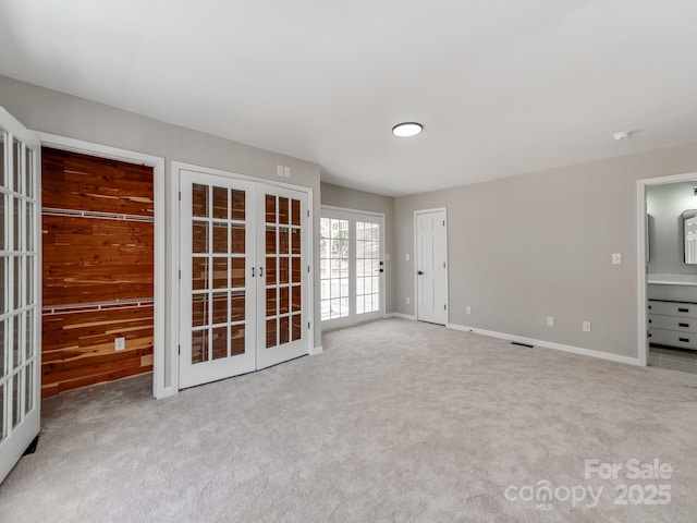 carpeted empty room featuring french doors and baseboards