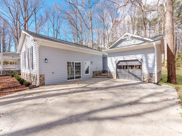 view of side of home with an outbuilding, stone siding, and concrete driveway