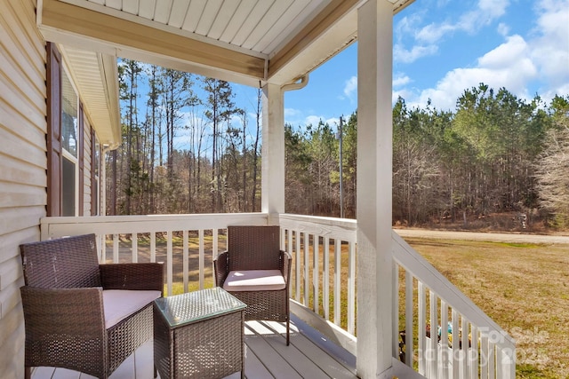 wooden deck with a yard and a view of trees