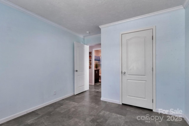 spare room featuring ornamental molding, a textured ceiling, and baseboards