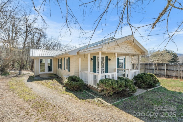 bungalow featuring metal roof, a porch, driveway, and fence