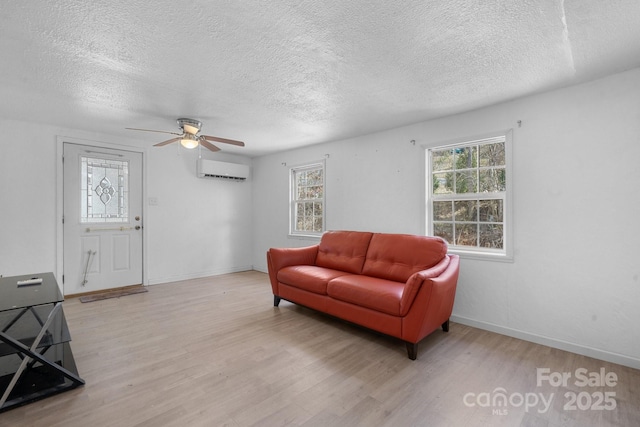 living area with wood finished floors, a wealth of natural light, and a wall mounted AC