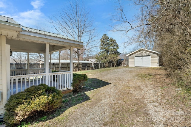 view of yard with an outbuilding, a detached garage, fence, and dirt driveway