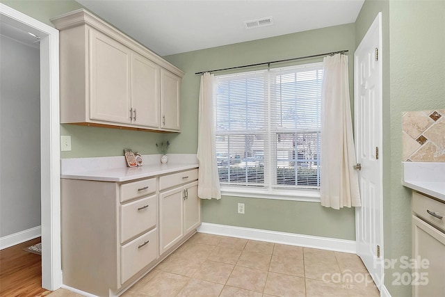 kitchen featuring light countertops, light tile patterned flooring, visible vents, and baseboards