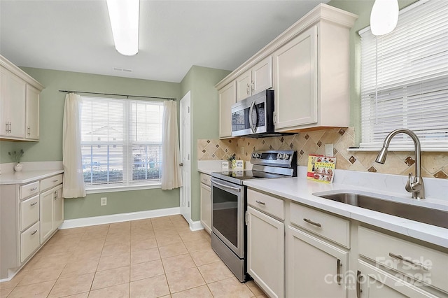 kitchen featuring decorative backsplash, appliances with stainless steel finishes, light countertops, and a sink