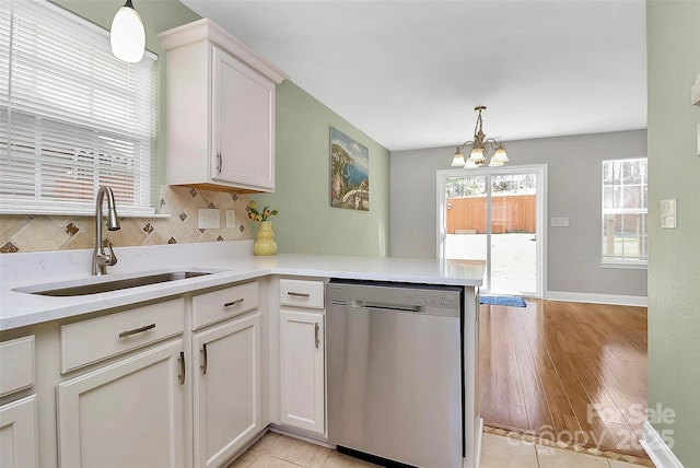 kitchen with hanging light fixtures, dishwasher, a peninsula, and a sink