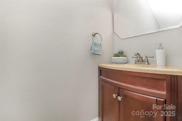 bathroom with a textured wall and vanity