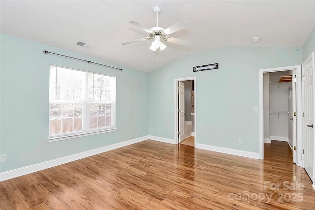 spare room with visible vents, light wood-style flooring, vaulted ceiling, ceiling fan, and baseboards