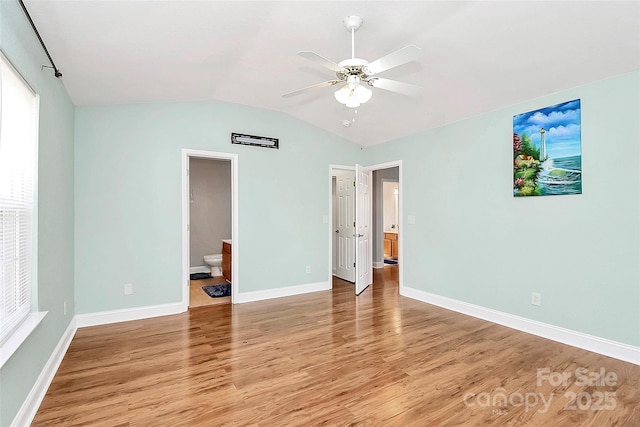 unfurnished bedroom featuring light wood-type flooring, baseboards, lofted ceiling, and ensuite bath