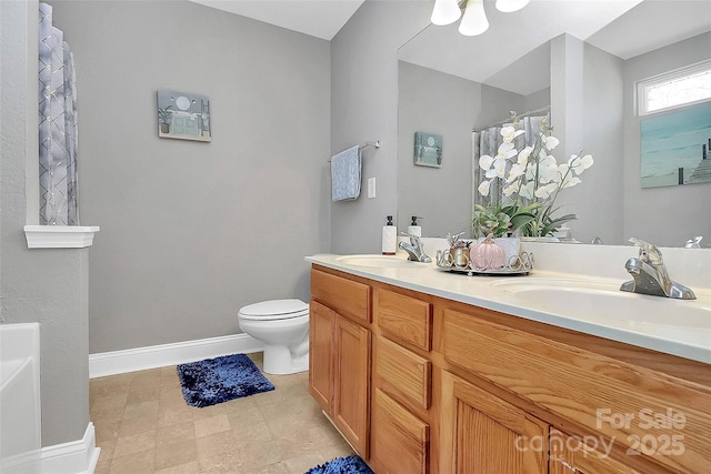 bathroom featuring toilet, curtained shower, baseboards, and a sink