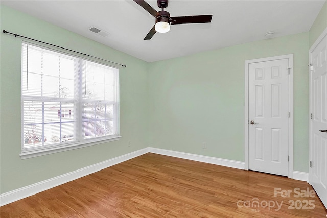 unfurnished bedroom featuring baseboards, a ceiling fan, visible vents, and light wood-style floors